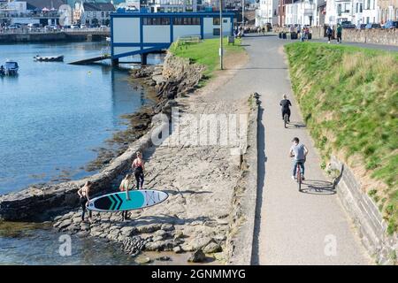 Paddleboarders e ciclisti a Portrush Harbour, Portrush (Port Rois), County Antrim, Irlanda del Nord, Regno Unito Foto Stock