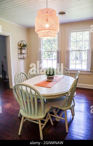 Una piccola sala da pranzo con un'illuminazione in rattan di tendenza e un tavolo da pranzo dipinto di blu Foto Stock