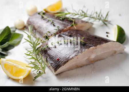 Due pezzi di pesce halibut fresco con erbe e limone Foto Stock