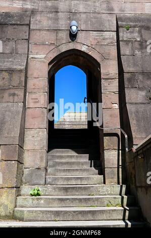 Chester, Inghilterra - Luglio 2021: Serie di ripidi gradini attraverso un arco di pietra sul sentiero intorno alle antiche mura della città Foto Stock