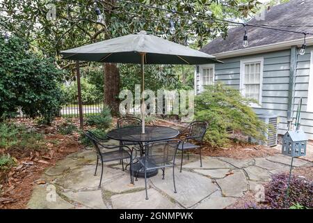 Cortile di una casa con un tavolo da patio e unbrella e alberi Foto Stock