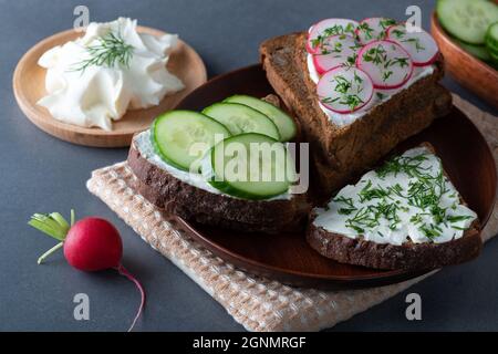 Sandwich con ravanello di formaggio morbido e cetrioli su un taglio di legno Foto Stock