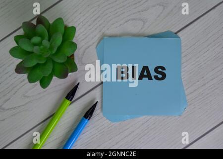 Bias scrivere su note appiccicose isolato su tavola di legno. Foto Stock