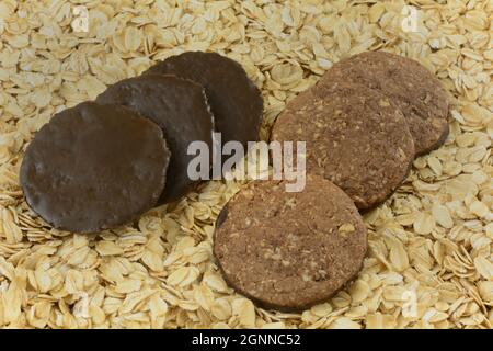 Entrambi i lati di biscotti di avena ricoperti di cioccolato su sfondo di avena arrotolata Foto Stock