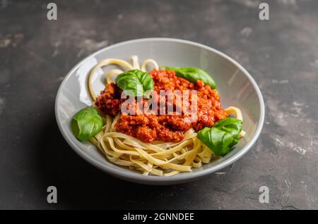 Tradizionale bolognese di pasta con manzo e pomodori sullo sfondo rustico. Messa a fuoco selettiva. Foto Stock
