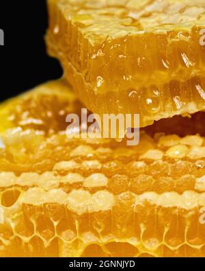Primo piano di dolci fette di miele biologico su sfondo scuro. Agente antibatterico, antimicotico e antivirale naturale Foto Stock