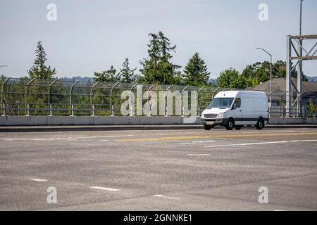 Mini furgone industriale compatto bianco di piccole dimensioni con vano di carico per le consegne locali e le esigenze delle piccole imprese che funzionano sull'ampia linea highwa multilinea Foto Stock