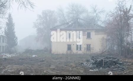 Una casa in legno abbandonata a due piani sulla strada in una giornata di nebbia Foto Stock