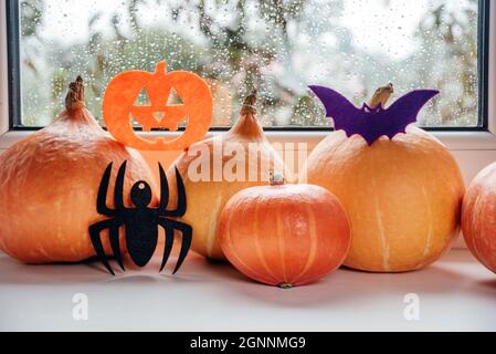 Zucche con ornamenti fatti a mano in feltro di Halloween sullo sfondo del davanzale, decorazioni casalinghi di Halloween Foto Stock
