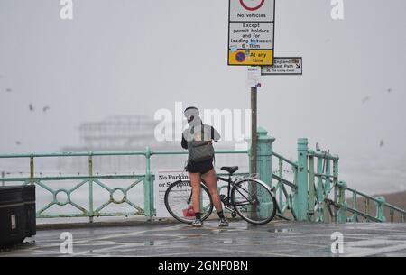 Brighton UK 27 Settembre 2021 - Un ciclista sul lungomare di Brighton come il tempo bagnato e ventoso sweep attraverso la Gran Bretagna oggi : Credit Simon Dack / Alamy Live News Foto Stock