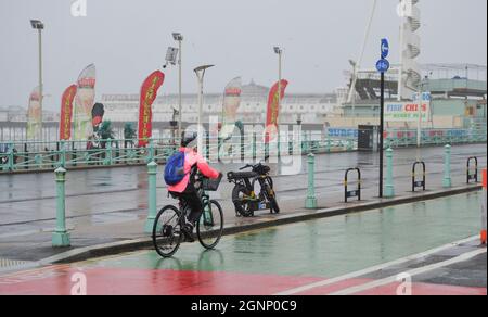 Brighton UK 27 settembre 2021 - Un ciclista batte attraverso il vento e la pioggia lungo il lungomare di Brighton mentre il tempo tempesta passa attraverso la Gran Bretagna oggi : Credit Simon Dack / Alamy Live News Foto Stock