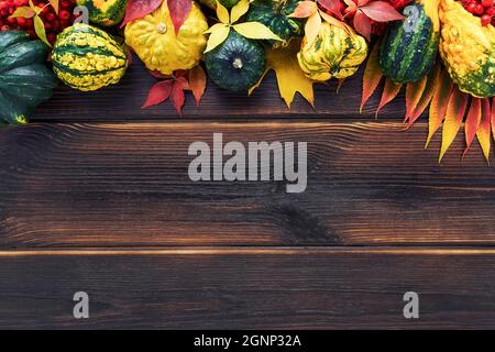 Sfondo autunnale con zucche, caduta di foglie colorate su un tavolo di legno scuro. Felice concetto di Thanksgiving. Disposizione piatta, spazio di copia per il testo Foto Stock