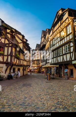 Grande vista sulla strada acciottolata di pietra Rue du Bain-aux-Plantes nel quartiere storico di Strasburgo la Petite France con negozi e ristoranti in... Foto Stock