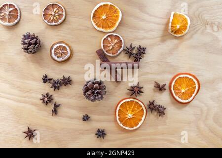 Composizione natalizia composta da coni, arance e limoni secchi, cannella e stelle di anice. Legno compensato sullo sfondo. Foto Stock