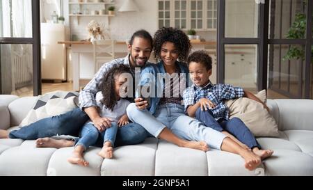 Felice famiglia afroamericana con due bambini che usano lo smartphone Foto Stock