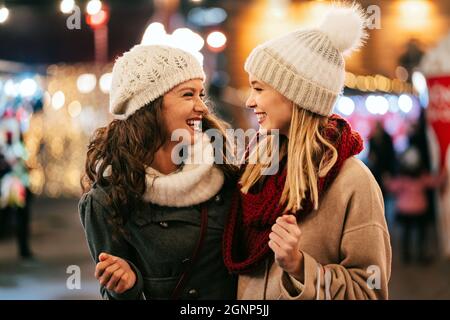 Allegre giovani donne amici a natale stanno avendo divertimento e shopping regali per la loro famiglia Foto Stock