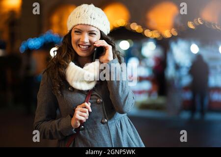 Ritratto di donna sorridente utilizzando il telefono cellulare in città in inverno. Concetto di comunicazione delle persone Foto Stock