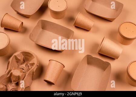 Articoli da tavola ecologici e confezioni di carta alimentare kraft su sfondo di carta kraft - tazze di carta, piatti e contenitori. Imballaggi alimentari sostenibili, zero Foto Stock