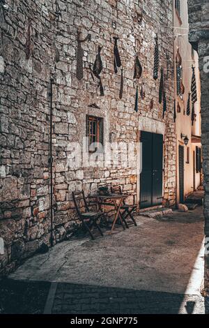 Vicolo di Rovigno, Croazia con sedie pieghevoli e tavoli di fronte ad una vecchia casa in mattoni Foto Stock