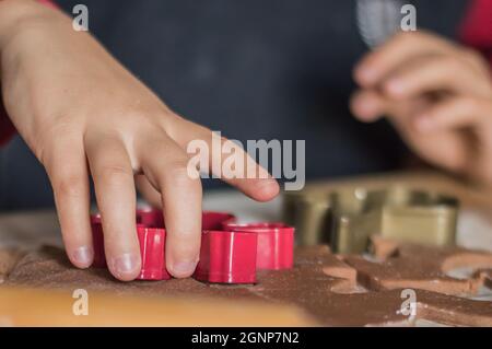 Le mani dei bambini fanno i biscotti di Capodanno dello zenzero.Preparazioni per Natale Foto Stock