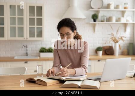 Studio femminile millenario online con libri di testo a casa Foto Stock