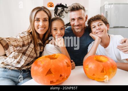 Famiglia bianca sorridente mentre si scatta una foto selfie con le zucche di Halloween a casa Foto Stock