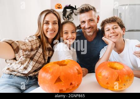 Famiglia bianca sorridente mentre si scatta una foto selfie con le zucche di Halloween a casa Foto Stock