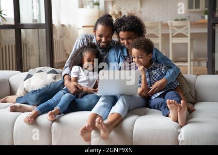 Felici genitori afroamericani con bambini che usano il computer portatile insieme Foto Stock