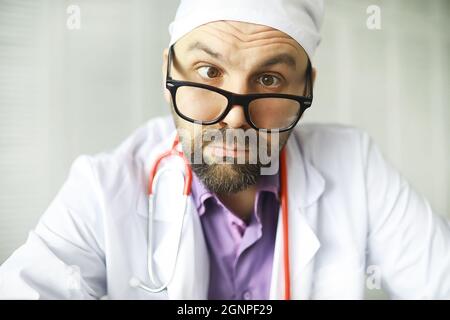 Un uomo con occhi incrociati sta guardando nel telaio. Malattia oculare. Il concetto di medico specialista pazzo. Vicino medico. Foto Stock