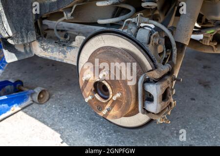 Disco del freno dell'auto usurato. Riparazione dei freni sulla vettura. Primo piano del disco del freno del veicolo. Auto su martinetto pneumatico Foto Stock