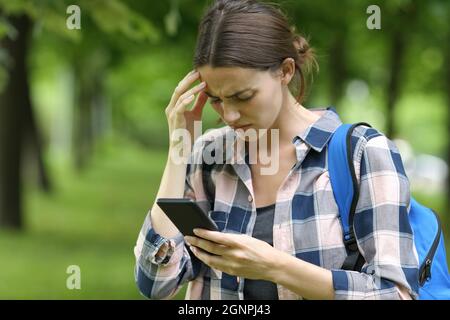 Studente interessato che controlla lo smartphone in un parcheggio Foto Stock