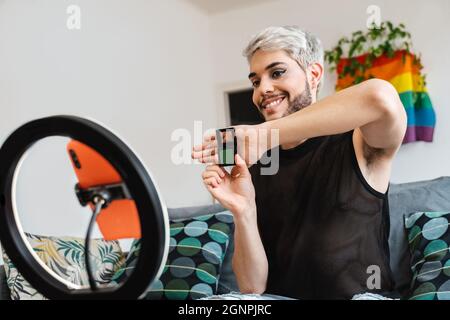 Transgender streaming online media trucco video tutorial con il telefono cellulare a casa - LGBTQ, gay, tecnologia trendy concetto - Focus in faccia Foto Stock