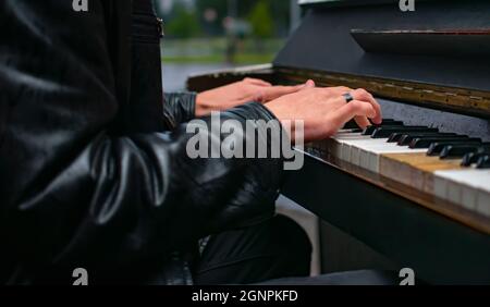 mani di un uomo, un ragazzo che suona una melodia sul pianoforte in autunno, su una strada serale in una piazza della città, parco Foto Stock