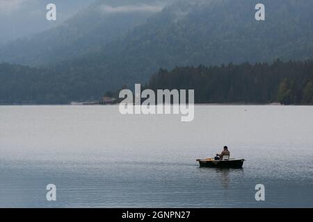 Pescatore in piccola barca sul lago al mattino gelido Foto Stock
