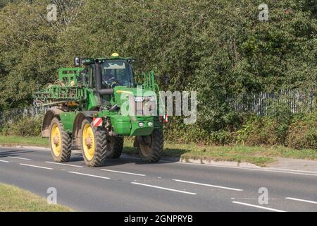 Comune irroratrice semovente agricola verde John Deere su strada rurale aperta in salita. Il modello Deere è R 4140i. Foto Stock