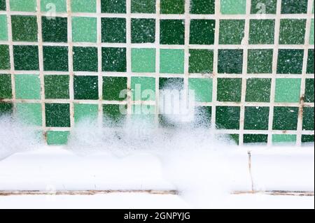 forgi su giunti tra le piastrelle in ceramica in bagno con una schiuma chimica pulente. pulizia di una muffa nera sporco sulle cuciture di piastrelle mosaico. sporco mo Foto Stock