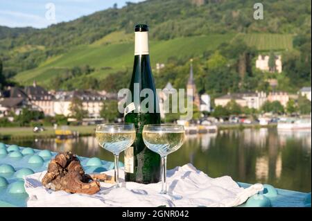 Vino riesling di qualità bianca in bottiglia verde servito sul vecchio ponte sul fiume Mosel con vista sulla città vecchia tedesca in giornata di sole Foto Stock