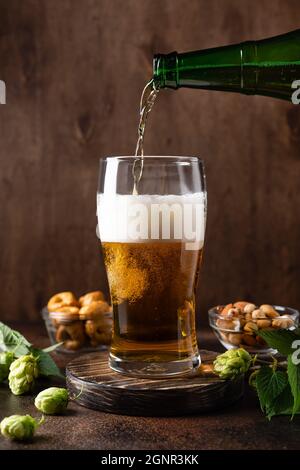 Versare la birra fresca dalla bottiglia in un bicchiere di birra Foto Stock