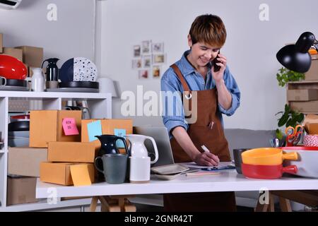 Imprenditore asiatico maturo, proprietario di affari usando l'indirizzo di controllo dello smartphone e i dettagli di consegna prima di spedire il prodotto. Commercio vendente in linea Foto Stock