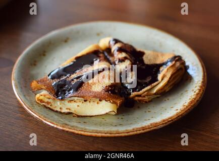 Le crepes sono su un piatto, sgocciolato di cioccolato. Pancake sottili. Dolce dessert. Foto Stock