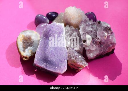 Belle gemme, geode di ametista e drusi di ametista minerale viola naturale su uno sfondo rosa brillante. Ametisti e quarzo rosa. Grande c Foto Stock