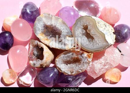 Belle gemme, geode ametista e drusi di ametista minerale viola naturale su uno sfondo rosa. Ametisti e quarzo rosa. Grandi cristalli di Foto Stock