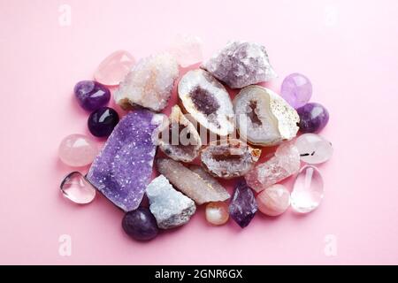 Belle gemme, geode ametista e drusi di ametista minerale viola naturale su uno sfondo rosa. Ametisti e quarzo rosa. Grandi cristalli di Foto Stock