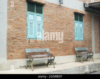 Edificio in mattoni con finestre e panchine in legno blu Foto Stock