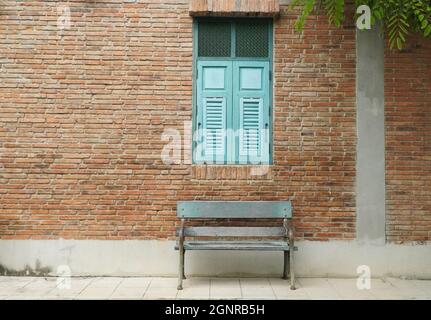 Edificio in mattoni con finestre e panca in legno blu Foto Stock