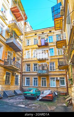 Il vecchio cantiere shabby dell'edificio vivente a più piani con auto d'epoca parcheggiate di fronte alle finestre, Odessa, Ucraina Foto Stock