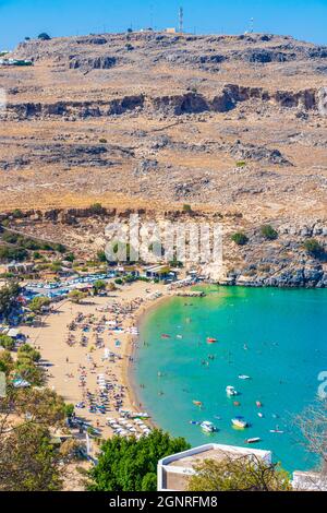 Lindos Beach vista panoramica baia con mare turchese chiaro barche turisti e sole su Rodi Grecia. Foto Stock