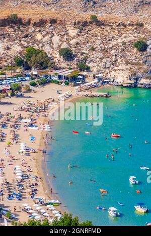 Lindos Beach vista panoramica baia con mare turchese chiaro barche turisti e sole su Rodi Grecia. Foto Stock