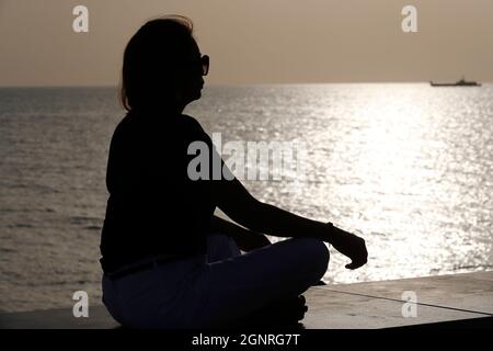Silhouette al tramonto di donna fedele che prega. Concetto di religione, fede, preghiera e spiritualità. Foto Stock