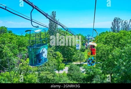 Godetevi il giro in cabinovia retrò sopra la lussureggiante foresta verde con una vista della costa del Mar Nero all'orizzonte, Odessa, Ucraina Foto Stock